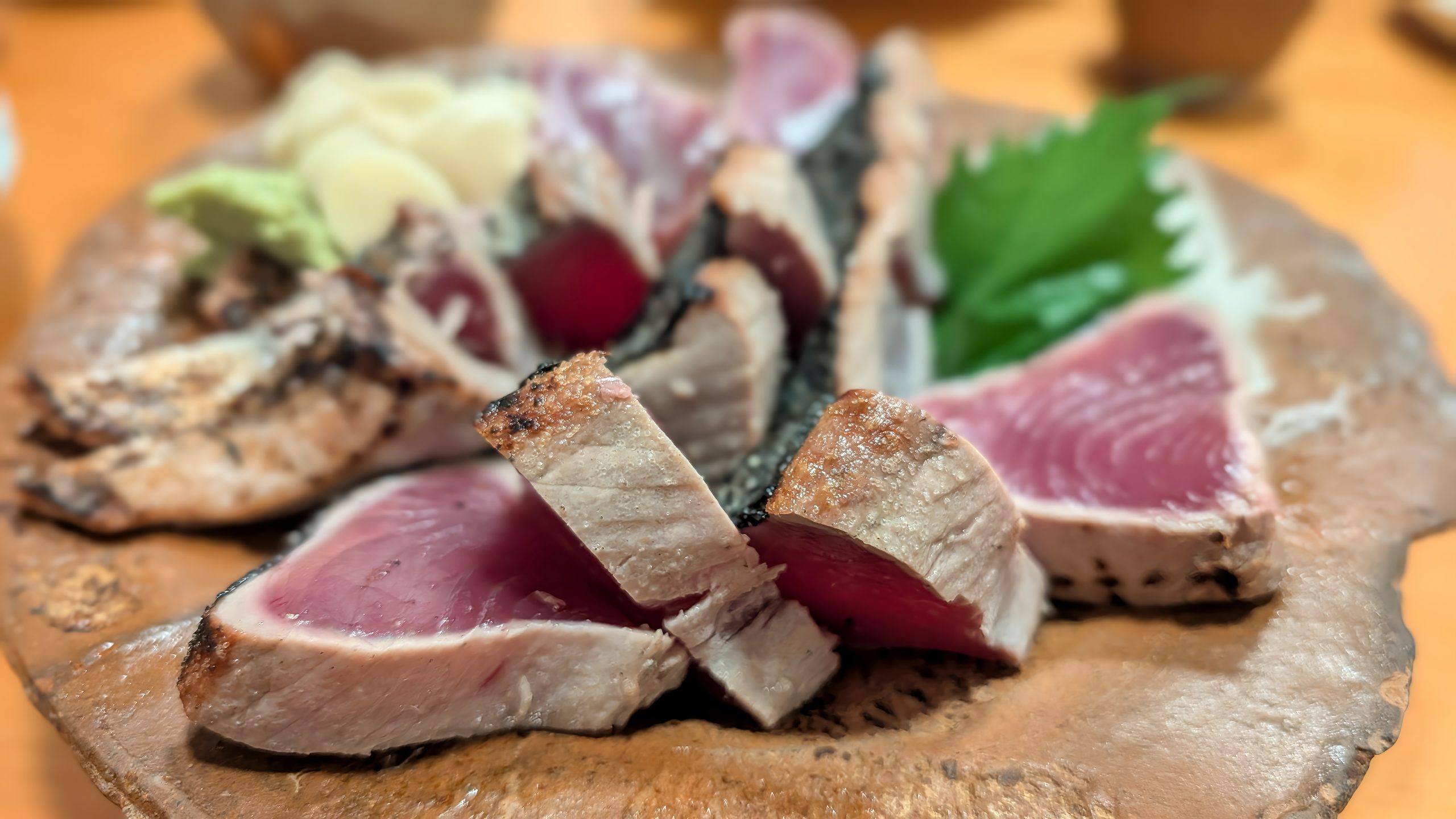 輪切りのにんにくとワサビでいただくカツオのたたき(表面には塩がまぶしてある)